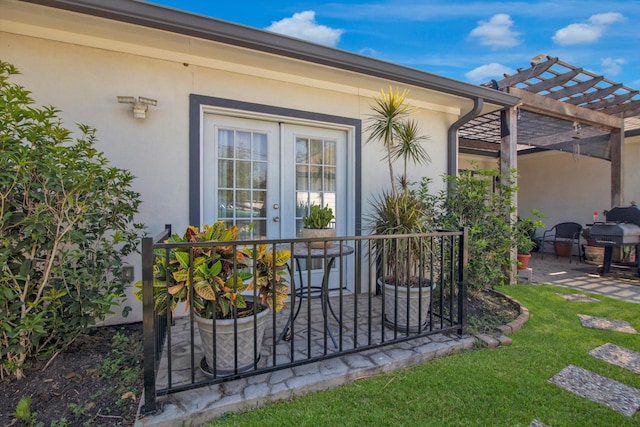 view of exterior entry featuring a pergola, a patio area, french doors, and a yard