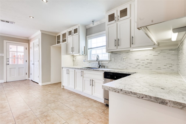 kitchen featuring dishwasher, sink, white cabinets, light stone counters, and decorative backsplash