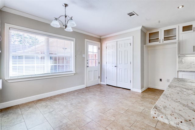 interior space with light tile patterned floors, ornamental molding, and an inviting chandelier