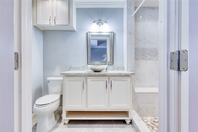 bathroom with vanity, a tile shower, toilet, and tile patterned floors