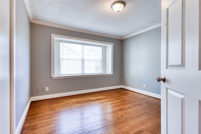 spare room with crown molding, a textured ceiling, and light wood-type flooring