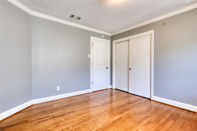 unfurnished bedroom featuring crown molding, light hardwood / wood-style flooring, and a textured ceiling