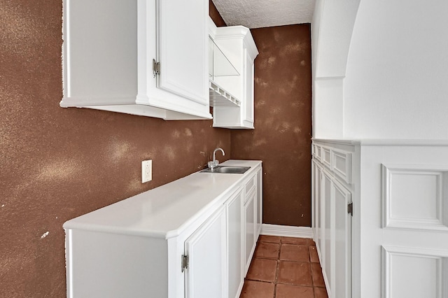 laundry room with tile patterned floors, sink, stacked washing maching and dryer, and a textured ceiling