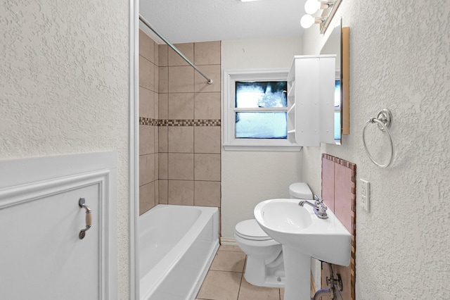 bathroom featuring tile patterned flooring, tiled shower / bath, a textured ceiling, and toilet