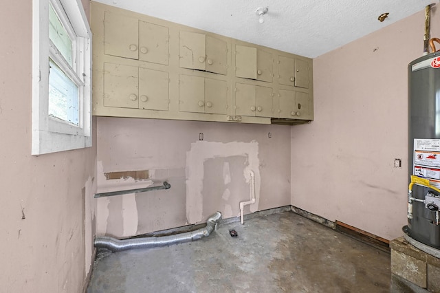 laundry room featuring gas water heater and a textured ceiling