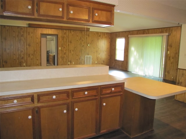 kitchen featuring kitchen peninsula, wooden walls, and dark hardwood / wood-style flooring