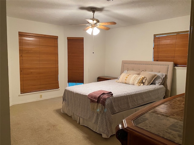 carpeted bedroom with ceiling fan and a textured ceiling