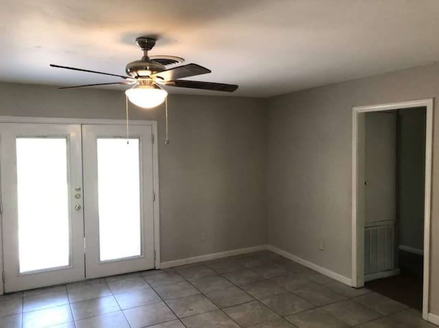 tiled spare room featuring french doors and ceiling fan