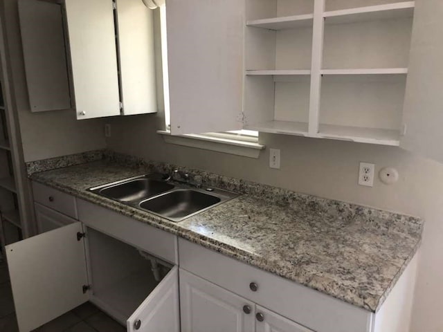 kitchen with white cabinetry, light stone countertops, sink, and dark tile patterned floors