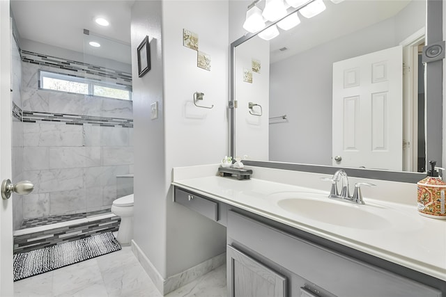 bathroom featuring a tile shower, vanity, and toilet