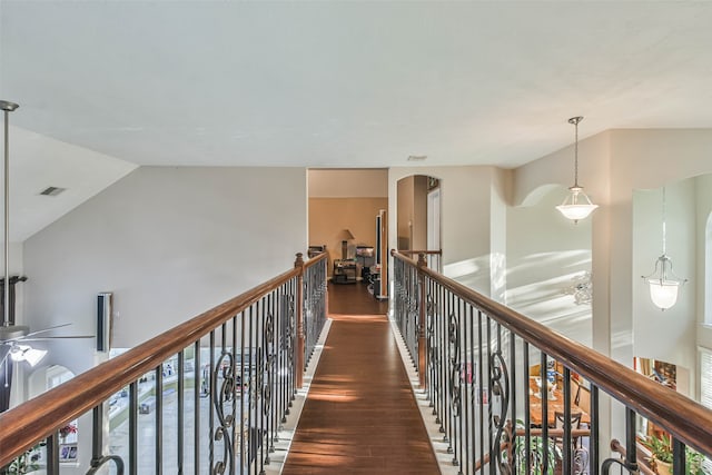 corridor with a healthy amount of sunlight, vaulted ceiling, and dark wood-type flooring