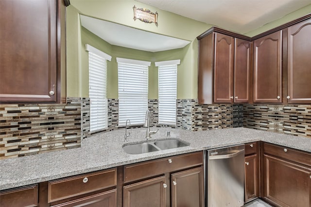 kitchen featuring stainless steel dishwasher, sink, dark brown cabinets, and light stone counters