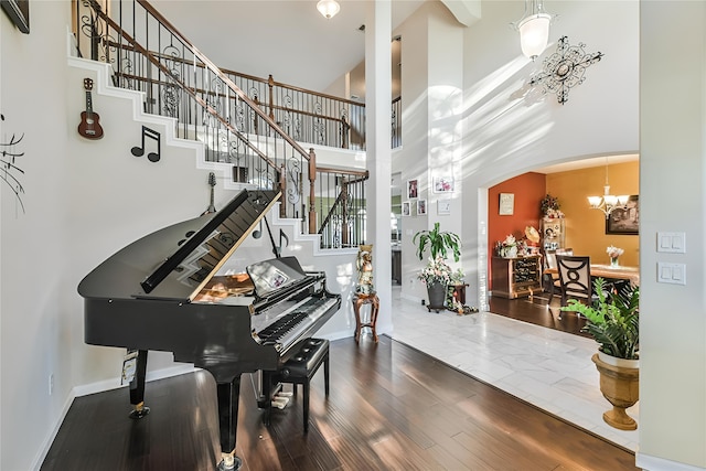 misc room featuring a towering ceiling, an inviting chandelier, and hardwood / wood-style floors