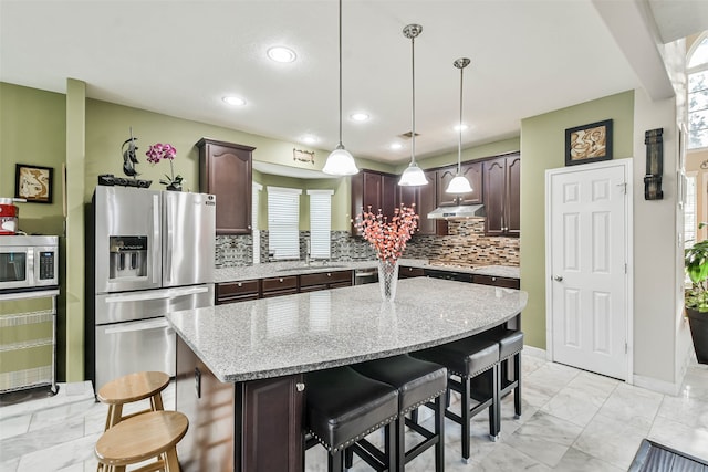 kitchen with a kitchen island, appliances with stainless steel finishes, decorative light fixtures, and dark brown cabinets