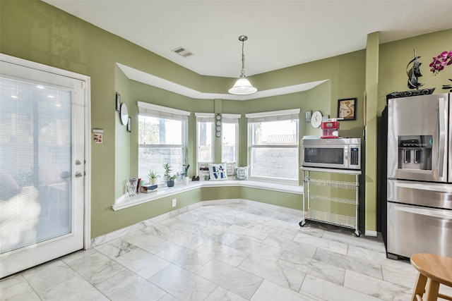 kitchen with a wealth of natural light, hanging light fixtures, and appliances with stainless steel finishes