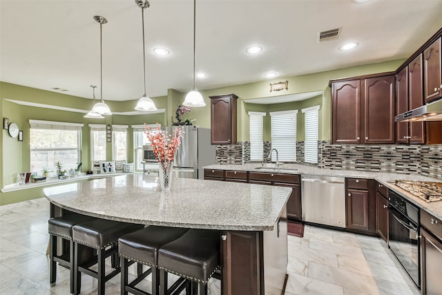 kitchen with a center island, decorative light fixtures, stainless steel appliances, decorative backsplash, and sink