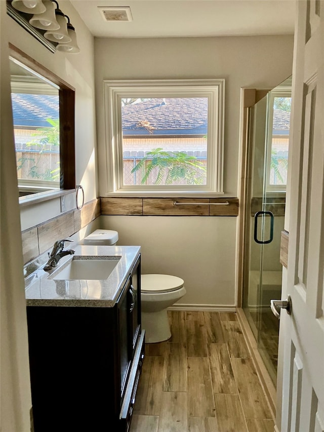 bathroom featuring vanity, a shower with shower door, hardwood / wood-style flooring, and toilet