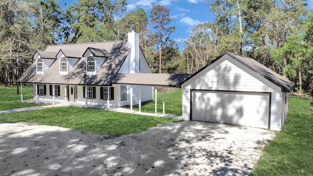 new england style home featuring covered porch, an outbuilding, a front lawn, and a garage