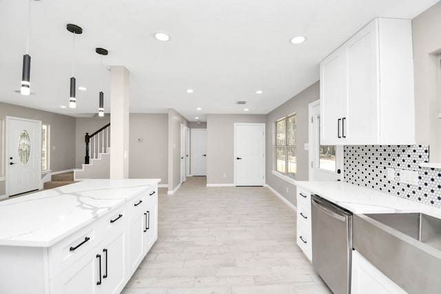 kitchen with backsplash, decorative light fixtures, stainless steel dishwasher, white cabinets, and light stone counters