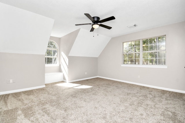 additional living space with ceiling fan, vaulted ceiling, plenty of natural light, and carpet floors