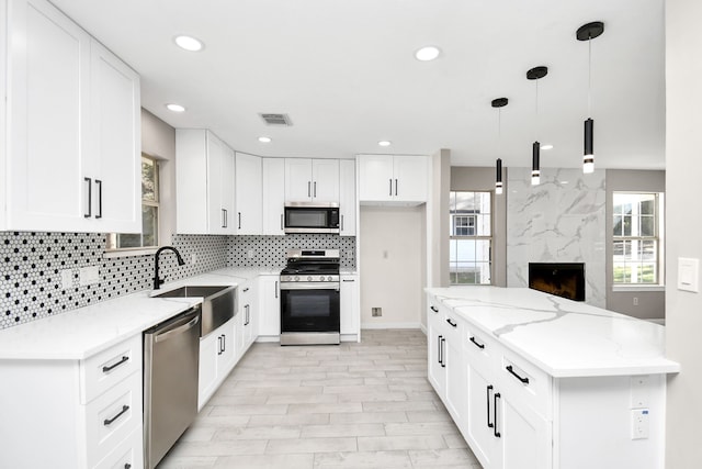 kitchen featuring white cabinets, decorative light fixtures, stainless steel appliances, and plenty of natural light