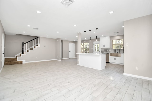 kitchen with dishwasher, a center island, light hardwood / wood-style floors, decorative light fixtures, and white cabinets