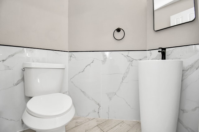 bathroom featuring toilet and tile walls