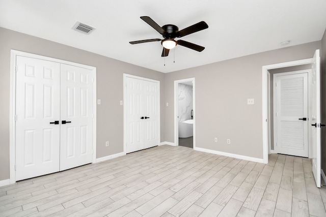 unfurnished bedroom featuring ceiling fan, multiple closets, light hardwood / wood-style flooring, and ensuite bath