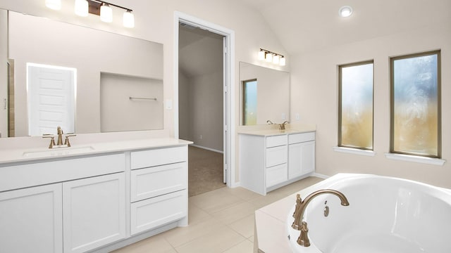 bathroom with lofted ceiling, vanity, a bathtub, and tile patterned floors