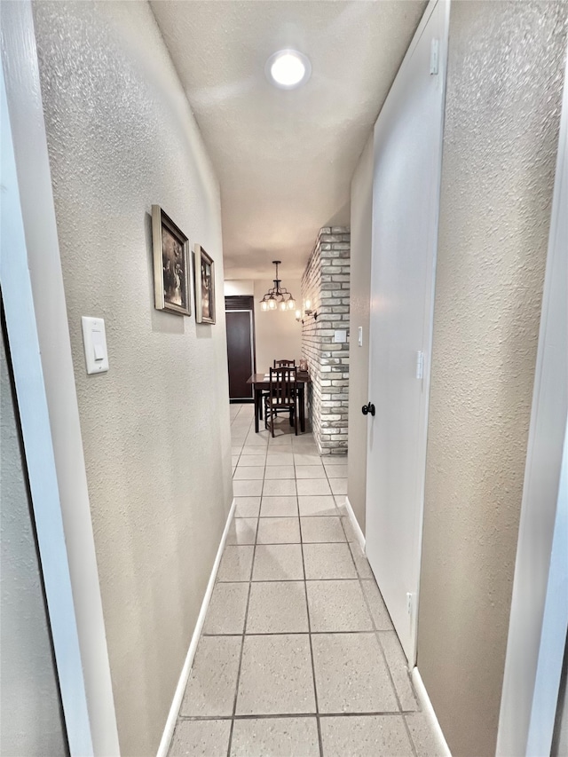 corridor with a chandelier and light tile patterned floors