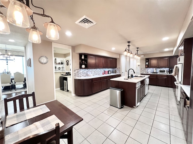 kitchen with backsplash, sink, an island with sink, and hanging light fixtures