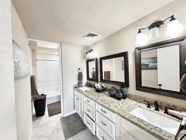 bathroom featuring vanity, a textured ceiling, and tub / shower combination