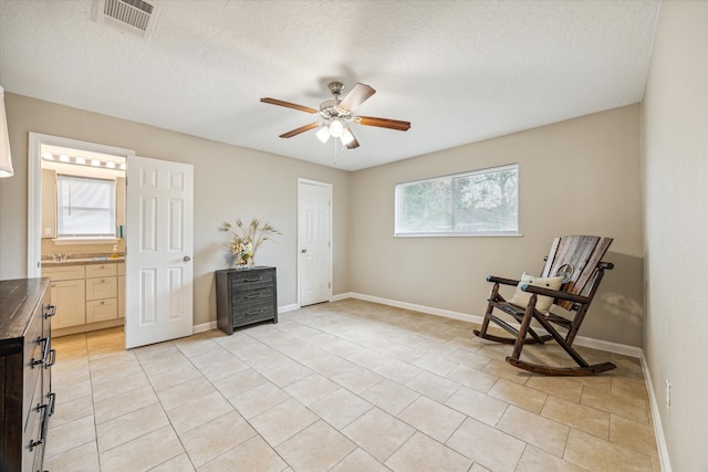 sitting room with a textured ceiling, light tile patterned floors, and ceiling fan