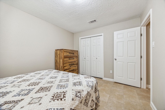 tiled bedroom with a textured ceiling and a closet