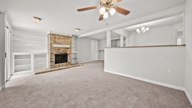 unfurnished living room with ceiling fan with notable chandelier, carpet flooring, built in features, and a brick fireplace