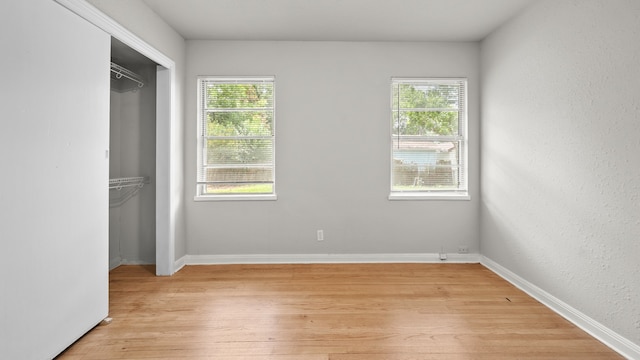 unfurnished bedroom with multiple windows, a closet, and light wood-type flooring