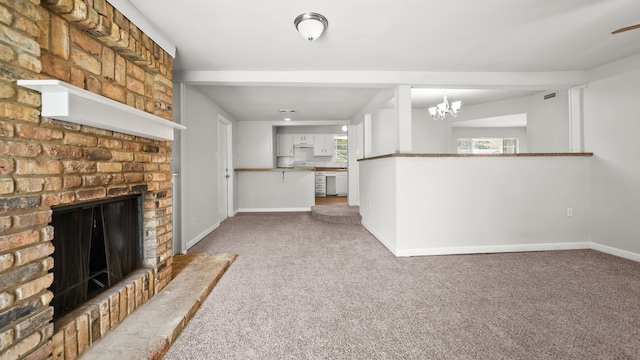 unfurnished living room featuring a notable chandelier, carpet floors, and a brick fireplace