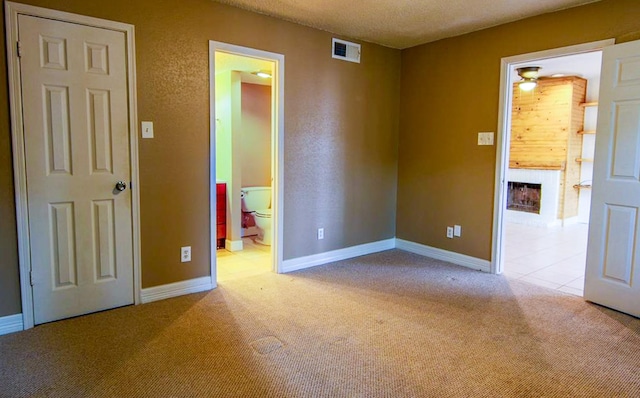 12100 Melville Dr Unit 402D, Montgomery, TX 77356 - unfurnished bedroom with carpet flooring, baseboards, a fireplace, ensuite bath, and a textured ceiling