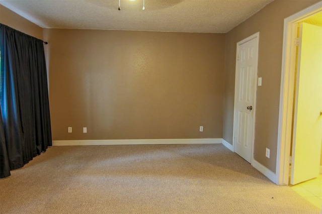 unfurnished room with ceiling fan, a textured ceiling, and light colored carpet