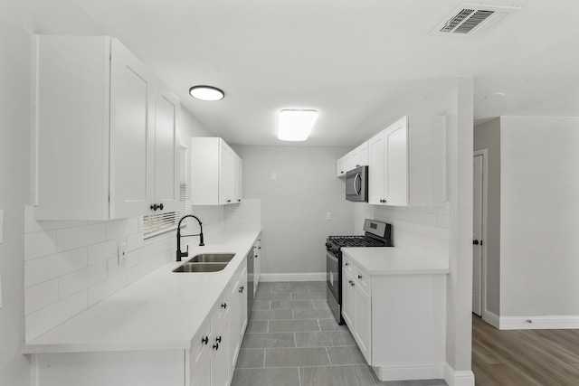 kitchen with white cabinets, dark hardwood / wood-style flooring, backsplash, sink, and stainless steel appliances