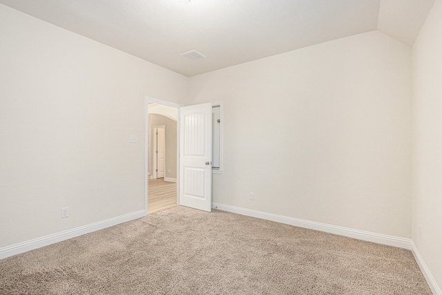 carpeted spare room with vaulted ceiling