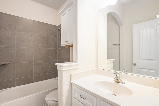 full bathroom featuring toilet, tiled shower / bath combo, vanity, and a textured ceiling