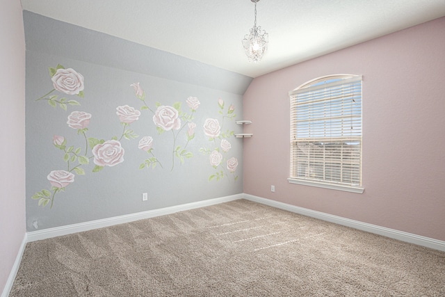 carpeted spare room featuring vaulted ceiling