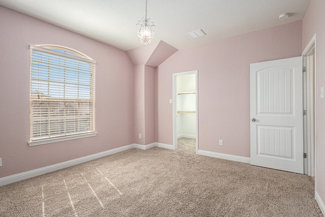 unfurnished bedroom featuring a closet, a spacious closet, carpet, and vaulted ceiling