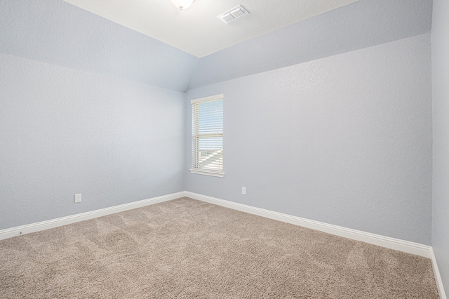 carpeted spare room featuring vaulted ceiling