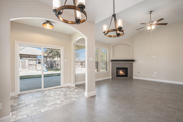 unfurnished living room featuring a tiled fireplace, tile patterned floors, vaulted ceiling, and ceiling fan with notable chandelier