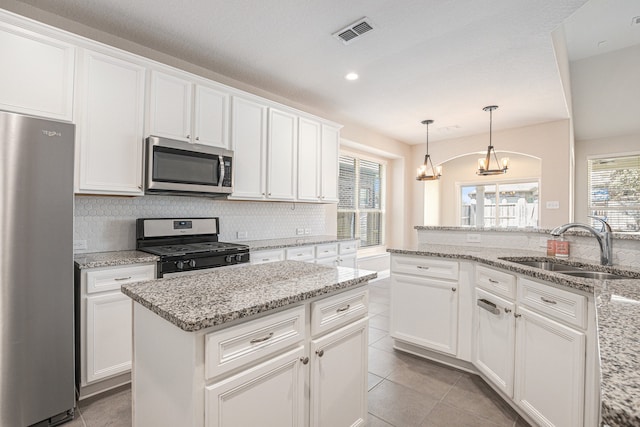 kitchen featuring sink, stainless steel appliances, pendant lighting, white cabinets, and a chandelier