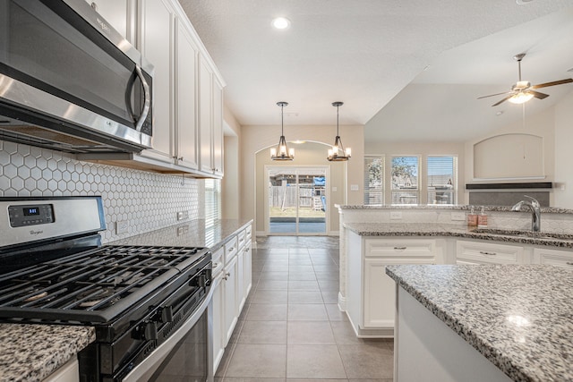 kitchen with tasteful backsplash, light stone counters, appliances with stainless steel finishes, white cabinetry, and sink