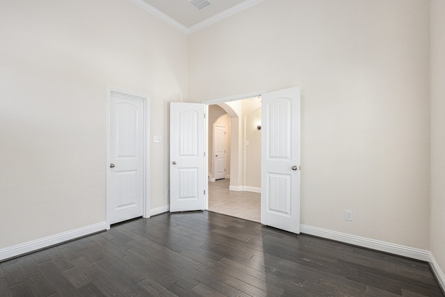 unfurnished room featuring ornamental molding, a towering ceiling, and dark hardwood / wood-style flooring