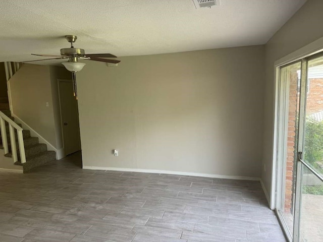 unfurnished room featuring a textured ceiling, light wood-type flooring, and ceiling fan